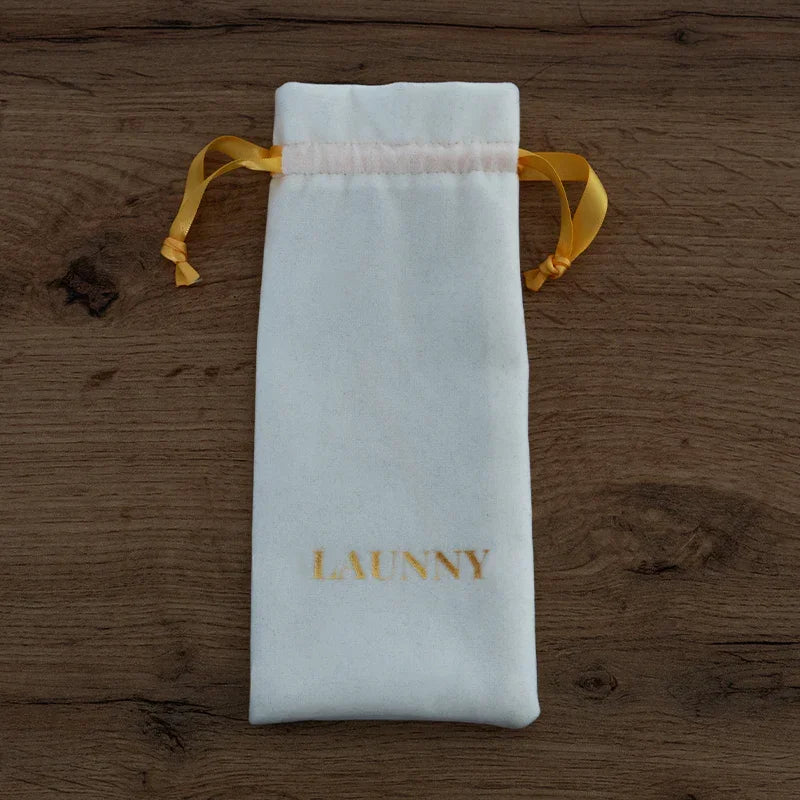 Pochon blanc en velours avec cordons jaunes et logo LAUNNY doré sur fond bois