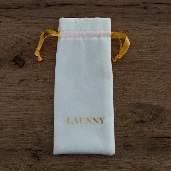 Pochon blanc en velours avec cordons jaunes et logo LAUNNY doré sur fond bois